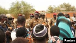 FILE: Burkina Faso President Lieutenant Colonel Paul-Henri Damiba talks to local people, after armed men killed civilians and militaries over the weekend in Seytenga, at airport in Dori, Burkina Faso 6.15.2022