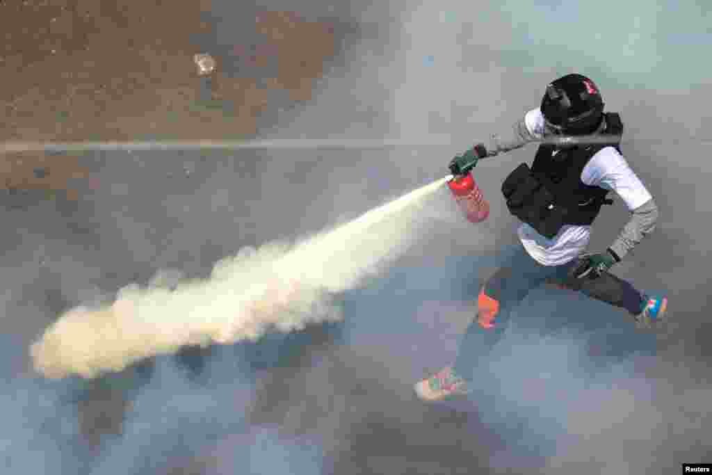 A protester sprays a fire extinguisher as demonstrators clash with riot police police during a protest against the military coup in Yangon, Myanmar, February 28, 2021.