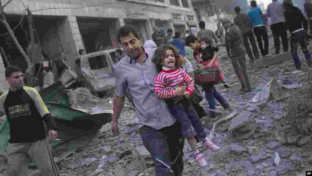 Palestinians flee their homes after an Israeli forces strike on nearby a sports field in Gaza City, November 19, 2012.