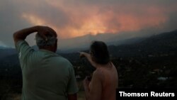 مردم در حال نظاره آتش‌سوزی طبیعی در منطقه کوهستانی لارناکا در قبرس هستند (منبع: رویترز)