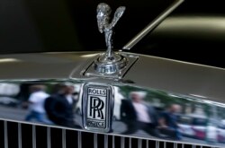 FILE - Pedestrians are reflected in the front of a Rolls-Royce in a London showroom, July 8, 2014. A reality TV personality in Georgia is accused of using a $2 million small-business loan to buy a Rolls-Royce.