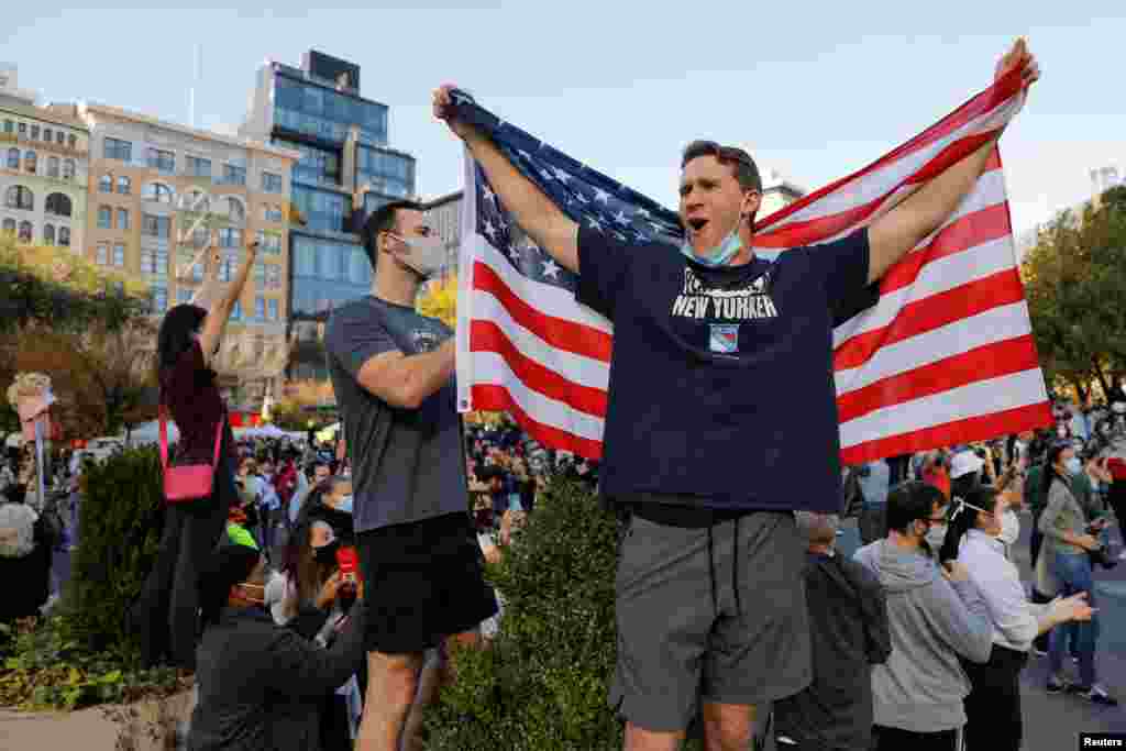 A man holds U.S. flag as people celebrate media announcing that Democratic U.S. presidential nominee Joe Biden has won the 2020 U.S. presidential election on Union Square in Manhattan.