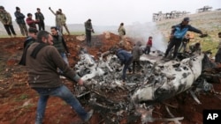 Syrians gather around a wreckage of a government military helicopter that was shot down in the countryside west of the city of Aleppo, Feb. 14, 2020.