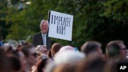 FILE - A sign of Democratic presidential candidate Sen. Bernie Sanders with 'Impeach Him' is held high during a protest by Washington area national and local organizations in Lafayette Square Park, in Washington, Friday, July 12, 2019.
