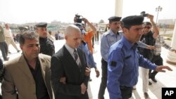 Iraqi policemen escort British security contractor, Danny Fitzsimons, outside a court in Baghdad, February 28, 2011