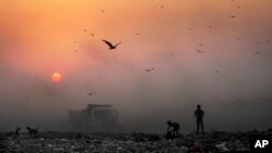 Asap tebal terlihat di angkasa sementara anak-anak pemulung mencari barang yang bisa didaur ulang di tempat pembuangan sampah di New Delhi, India. (Foto: Dok)