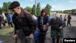 Residents from Vovchansk and nearby villages wait for buses amid an evacuation due to Russian shelling, amid Russia's attack on Ukraine, at an undisclosed location near the town of Vovchansk in the Kharkiv region, Ukraine, May 10, 2024.