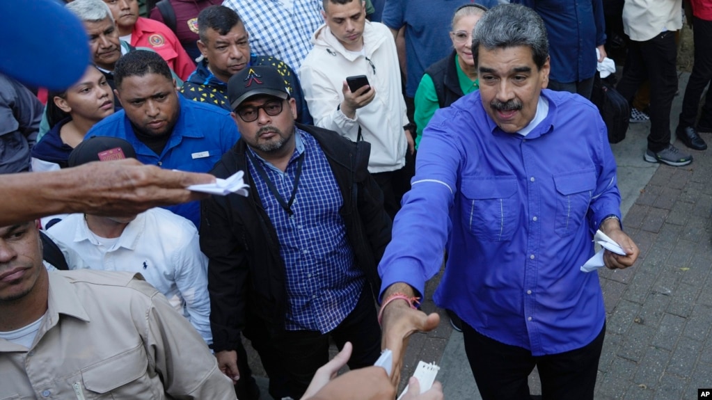 ARCHIVO - Ciudadanos entregan al presidente Nicolás Maduro papeles con peticiones durante un acto con representantes de las iglesias evangélicas de Venezuela, en Caracas, el 15 de mayo de 2024.