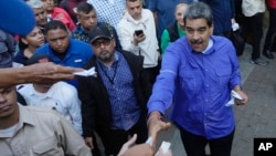ARCHIVO - Ciudadanos entregan al presidente Nicolás Maduro papeles con peticiones durante un acto con representantes de las iglesias evangélicas de Venezuela, en Caracas, el 15 de mayo de 2024.