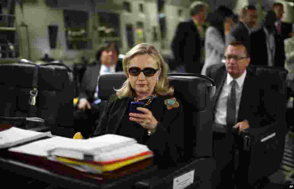 Menteri Luar Negeri AS Hillary Rodham Clinton mengecek Blackberry-nya dalam pesawat militer C-17 yang terbang dari Malta, di Laut Mediterania, menuju Tripoli, Libya. (AP/Kevin Lamarque, Pool, File)
