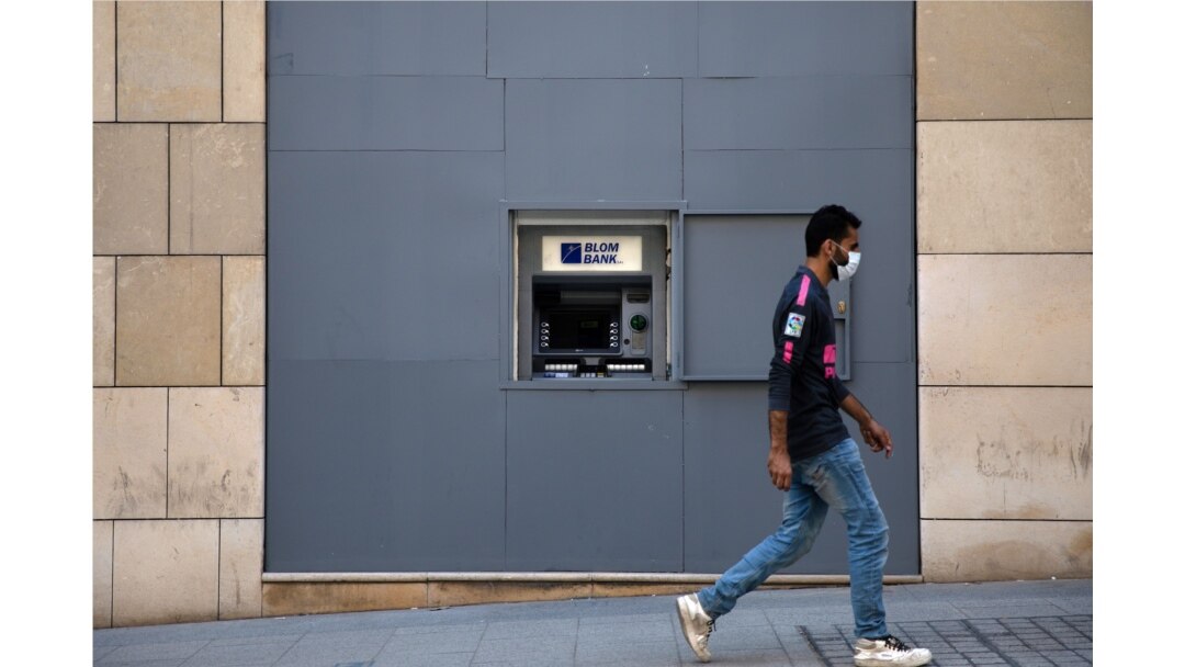 FILE - A man wearing a face mask walks past a fortified Blom Bank ATM machine, in Beirut, Lebanon, Aug. 21, 2020.