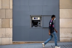 FILE - A man wearing a face mask walks past a fortified Blom Bank ATM machine, in Beirut, Lebanon, Aug. 21, 2020.