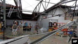 Ethan Hall, right, Michael Jenkins, center, and Nash Fralick examine damage to Tidewater Brewing Co. in Wilmington, N.C., after Hurricane Florence made landfall, Sept. 14, 2018.