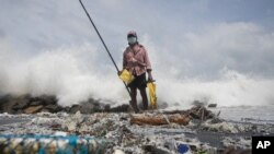 A Sri Lankan man fishes on a polluted beach filled with plastic pellets washed ashore from the fire-damaged container ship MV X-Press Pearl in Kapungoda, on the outskirts of Colombo, Sri Lanka, June 4, 2021.