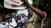 A Ugandan policeman holds up a newspaper, just before police fired tear gas to disperse the demonstration in downtown Kampala, Uganda on May 28, 2013.