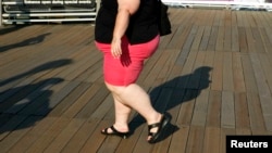 FILE - A woman walks along a boardwalk in New York. Lifestyle and lack of access to health care have been among the factors attributed to a rise in the mortality rate of white women in the United States.