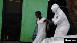 Petugas kesehatan membawa pasien perempuan yang diduga terjangkit virus Ebola ke dalam ambulans di Monrovia, Liberia (15/9). (Reuters/James Giahyue)