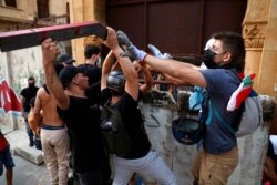 Anti-government protesters try to remove a blast wall that was set to protect the parliament building during a protest marking the first anniversary of the massive blast at Beirut's port, near Parliament Square, in Beirut, Lebanon, Aug. 4, 2021.