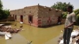 FILE - A man passes on the side of a flooded road in the town of Alkadro, about (20 km) north of the capital Khartoum, Sudan,. Taken 9.5.2020