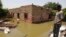 FILE - A man passes on the side of a flooded road in the town of Alkadro, about (20 km) north of the capital Khartoum, Sudan,. Taken 9.5.2020
