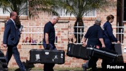 Petugas forensik kepolisian Australia membawa peralatan ke dalam rumah yang digerebek di Sydney, terkait dugaan terorisme (18/9). (Reuters/David Gray)