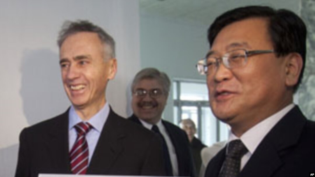 AP President Tom Curley, left, and Korean Central News Agency President Kim Pyong Ho hold an Associated Press Pyongyang sign before hanging it on the door of the new AP bureau in Pyongyang, Jan. 16, 2012.