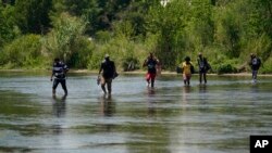 Un grupo de migrantes cruza el Río Bravo camino a entregarse al cruzar la frontera entre Estados Unidos y México, el 15 de junio de 2021, en Del Río, Texas.