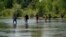 Un grupo de migrantes cruza el Río Bravo camino a entregarse al cruzar la frontera entre Estados Unidos y México, el 15 de junio de 2021, en Del Río, Texas. 