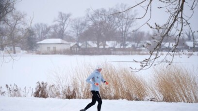 Una corredora recorre Washington Park mientras la tormenta invernal azota las montañas del oeste en Denver.