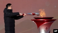 El viceprimer ministro de China, Han Zheng, enciende la antorcha olímpica antes del inicio del relevo para los Juegos Olímpicos de Invierno de Beijing 2022, en el parque olímpico de Beijing, el 2 de febrero de 2022.