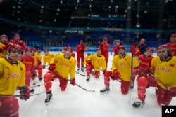 参加北京冬奥会的中国冰球队运动员在赛前练习时倾听教练讲话。（2022年1月30日）