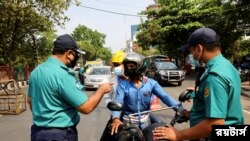 করোনাভাইরাস সংক্রমণ রোধে বাংলাদেশ সরকারের নেয়া নানা বিধিনিষেধের অংশ হিসাবে এক মোটরসাইকেল চালককে জিজ্ঞাসাবাদ করছেন পুলিশ। (ফাইল ছবি- মোহাম্মাদ পনির হোসেন/ রয়টার্স) 
