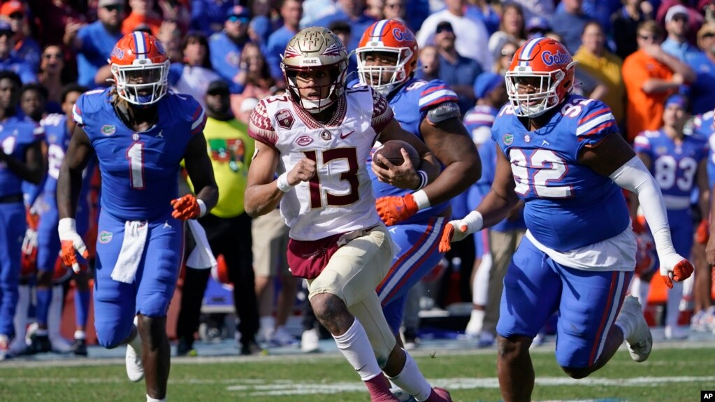 The Florida State quarterback is chased by players from Florida in the last game of the regular season for each team. Neither team won more games than it lost last year. (AP Photo/John Raoux)