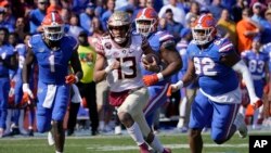 The Florida State quarterback is chased by players from Florida in the last game of the regular season for each team. Neither team won more games than it lost last year. (AP Photo/John Raoux)