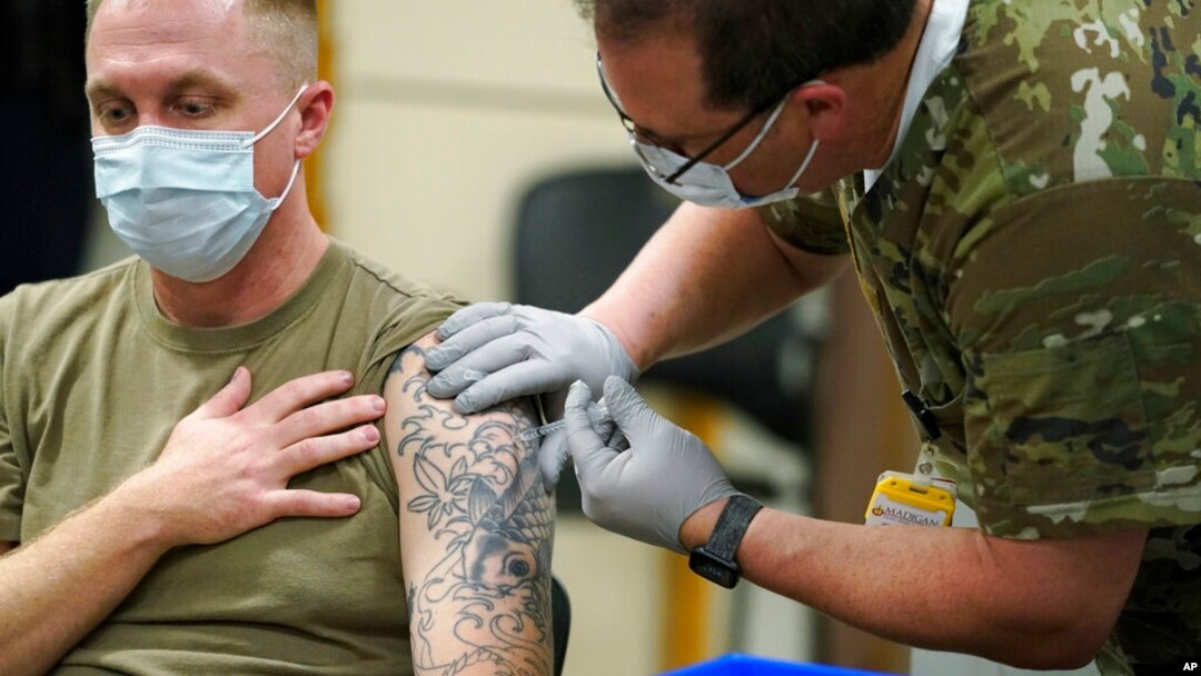 FILE - Staff Sgt. Travis Snyder, left, receives the first dose of the Pfizer COVID-19 vaccine given at Madigan Army Medical Center at Joint Base Lewis-McChord in Washington state, Dec. 16, 2020.
