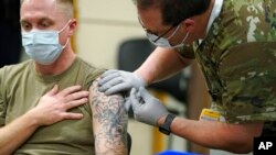 FILE - Staff Sgt. Travis Snyder, left, receives the first dose of the Pfizer COVID-19 vaccine given at Madigan Army Medical Center at Joint Base Lewis-McChord in Washington state, Dec. 16, 2020.