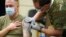FILE - Staff Sgt. Travis Snyder, left, receives the first dose of the Pfizer COVID-19 vaccine given at Madigan Army Medical Center at Joint Base Lewis-McChord in Washington state, Dec. 16, 2020.