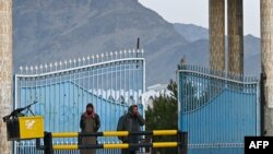 Taliban fighters stand guard at the main gate of Laghman University in Mihtarlam, Laghman province, Feb. 2, 2022. 