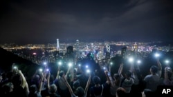 Demonstrators hold up their mobile phones as they form a human chain at the Peak, a tourist spot in Hong Kong, Sept. 13, 2019.