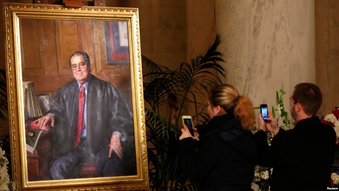 A couple takes photographs of a painting of late U.S. Supreme Court Justice Antonin Scalia in the Great Hall of the Supreme Court in Washington, Feb. 19, 2016.