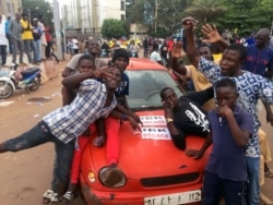 Opposition supporters react to the news of a possible mutiny of soldiers in the military base in Kati, outside the capital Bamako, at Independence Square in Bamako, Mali, Aug. 18, 2020.