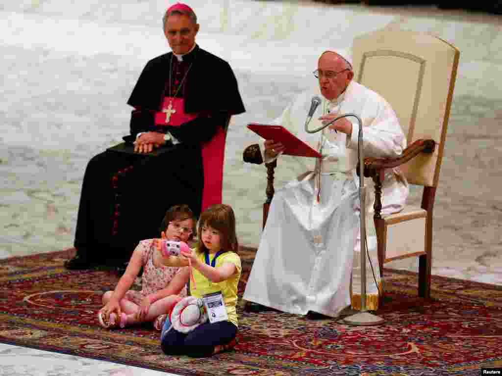 A child takes pictures in front of Pope Francis during a Jubilee for the sick and disabled in Paul VI hall at the Vatican, June 11, 2016.