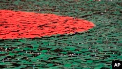 FILE - Bangladeshis flip colored cards to form the national flag during Victory Day celebrations in Dhaka, Bangladesh, Dec. 16, 2013.