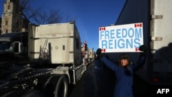 FILE - A supporter holds a sign while participating in a "Freedom Convoy" protesting COVID-19 vaccine mandates and restrictions in front of the Parliament of Canada, in Ottawa, Jan. 28, 2022.