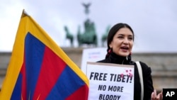 Seorang demonstran yang menentang Olimpiade Beijing 2022 terlihat berdiri di depan Gerbang Brandenburg di Berlin, Jerman, Selasa, 4 Januari 2022 . (Foto: AP)