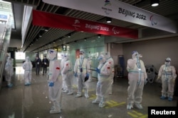 People wearing personal protective equipment (PPE), designed to prevent the spread of the coronavirus disease (COVID-19), stand inside Beijing Capital International Airport ahead of the Beijing 2022 Winter Olympics in Beijing, China January 31, 2022. (REUTERS/Phil Noble)