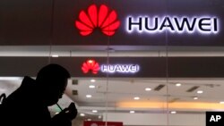 A man lights a cigarette outside a Huawei retail shop in Beijing, Dec. 6, 2018. 