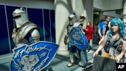 FILE - Attendees Michael Mijerark, left, and Ryan Trent, center, dress as knights from "Warcraft," at Comic-Con International in San Diego, July 19, 2018.