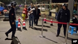 FILE - Residents walk past a security checkpoint at the close of a open-air market in Kashgar in western China's Xinjiang region, Nov. 4, 2017. Authorities are using detentions in political indoctrination centers and surveillance in efforts to control the Xinjiang region and its Uighurs, a Turkic-speaking Muslim minority Beijing fears could be influenced by extremism. 