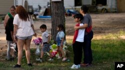 Varios vecinos colocan flores en el exterior de la vivienda en que fueron asesinados 5 hondureños en Cleveland, Texas, el 1 de mayo de 2023.